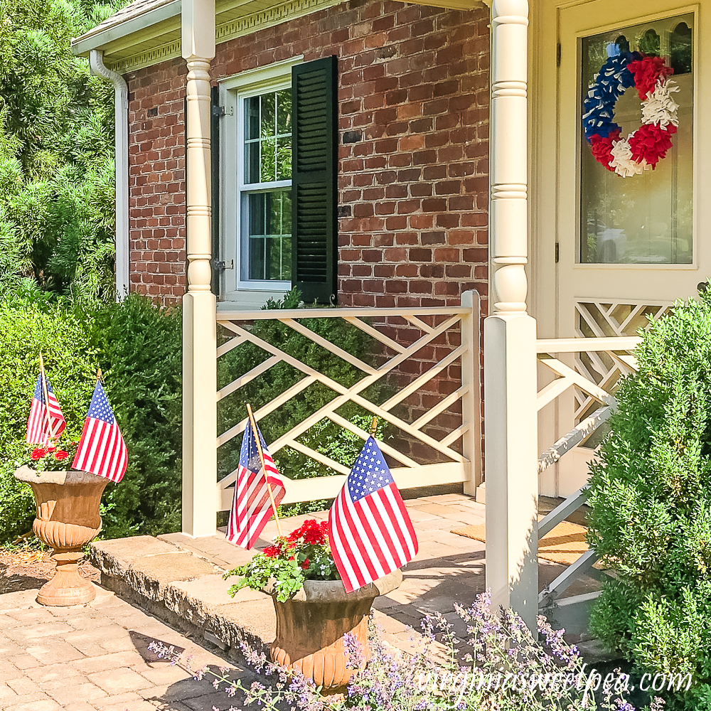 Home decorated patriotically with a red, white, and blue rag wreath and a flower pot with flags.