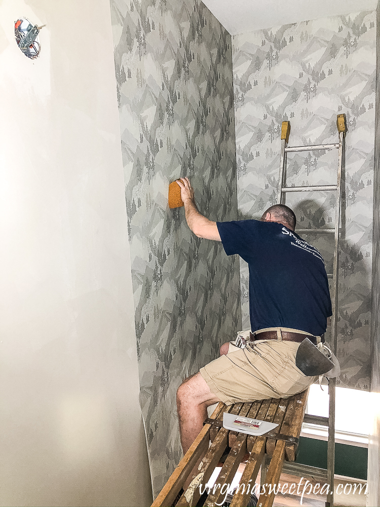 Installing wallpaper with a mountain and forest theme in a stairwell