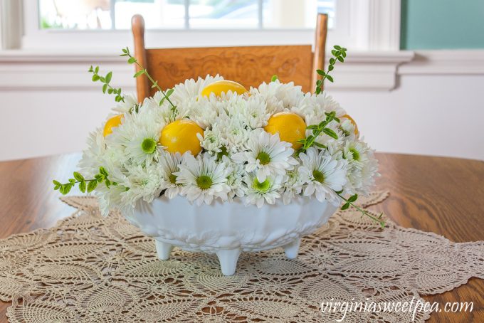 Flower arrangement with Chrysanthemums, and Lemon in a white Indiana milk glass footed fruit bowl.