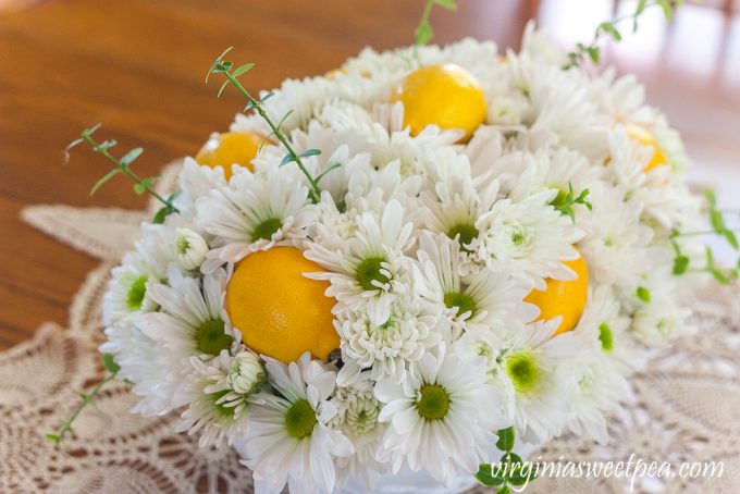 Flower arrangement with Chrysanthemums, and Lemon in a white Indiana milk glass footed fruit bowl.