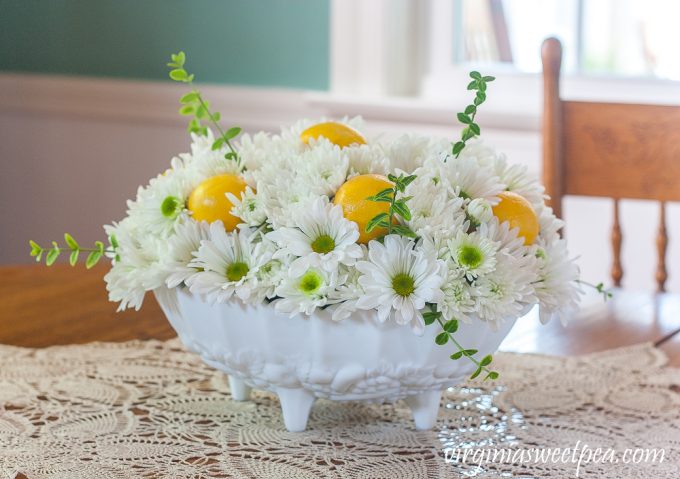 Flower arrangement with Chrysanthemums, and Lemon in a white Indiana milk glass footed fruit bowl.