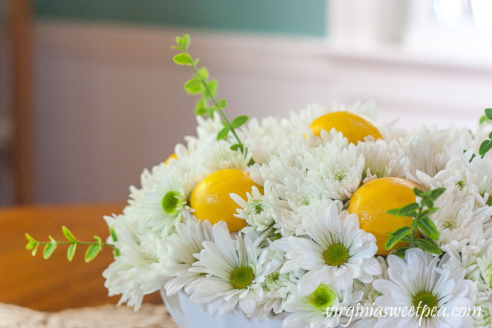 Flower arrangement with Chrysanthemums, and Lemon in a white Indiana milk glass footed fruit bowl.