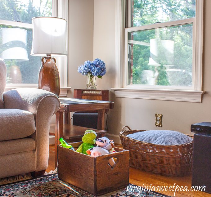 Vintage crate filled with dog toys and a vintage woven laundry basket filled with blankets