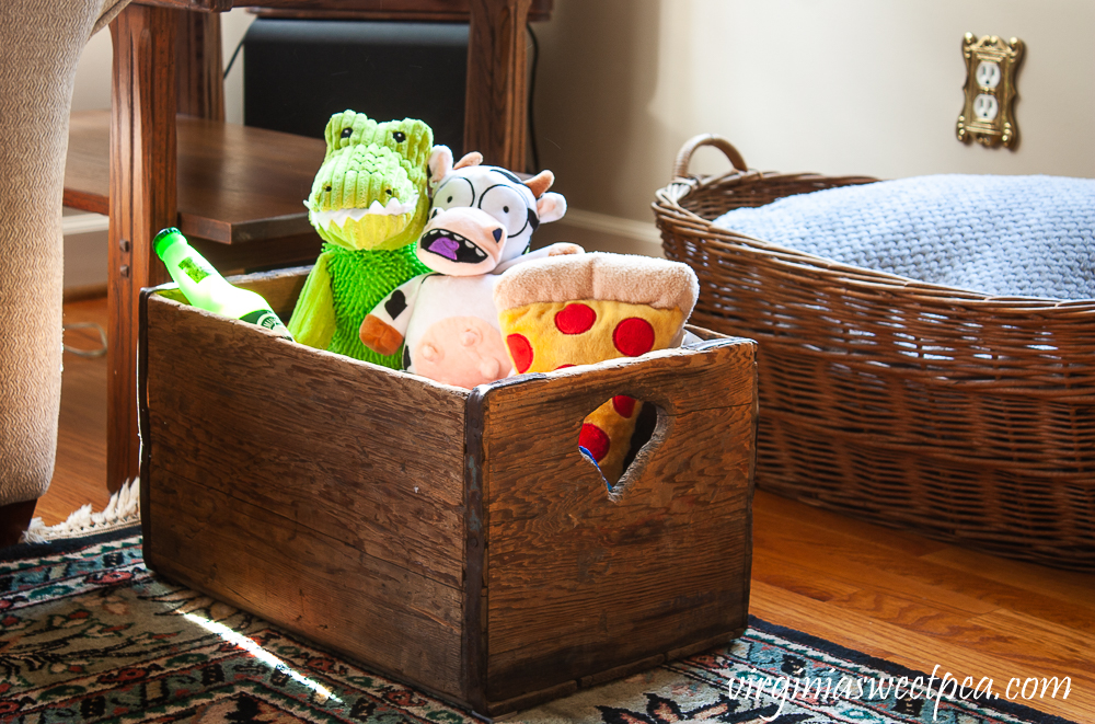 Vintage crate filled with dog toys and a vintage woven laundry basket filled with blankets