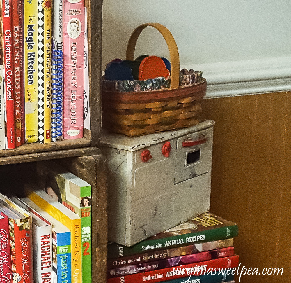 Cookbooks in vintage crates. Antique child stove with a basket filled with vintage cookie cutters.