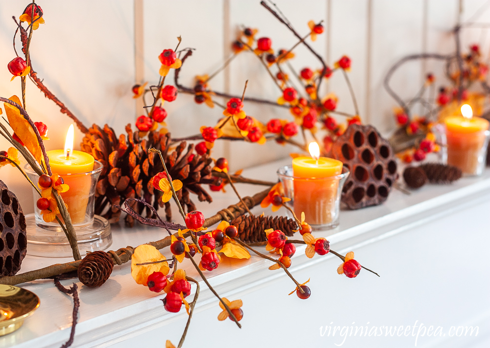 Nature inspired fall mantel decor with bittersweet, pine cones, and lotus pods