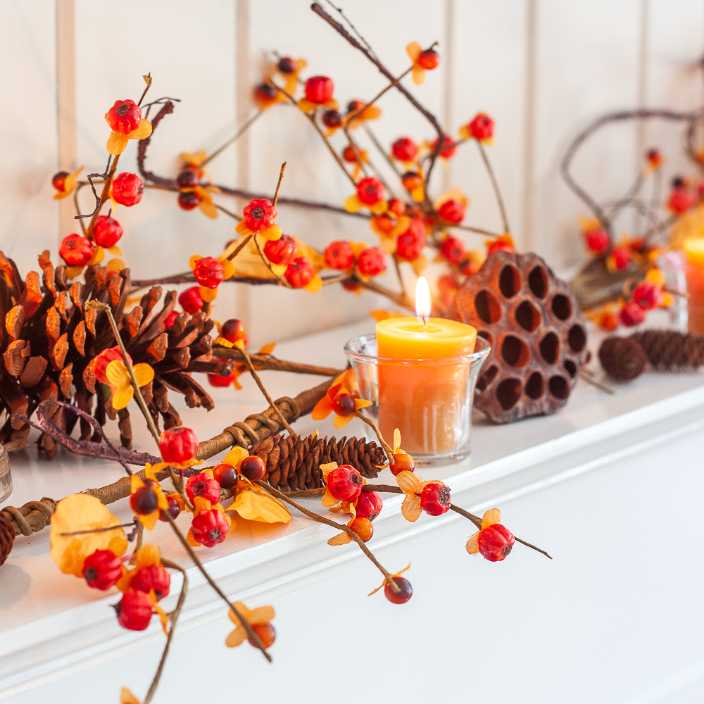 Fall mantel decorated with bittersweet, lotus pods, pine cones, and candles.