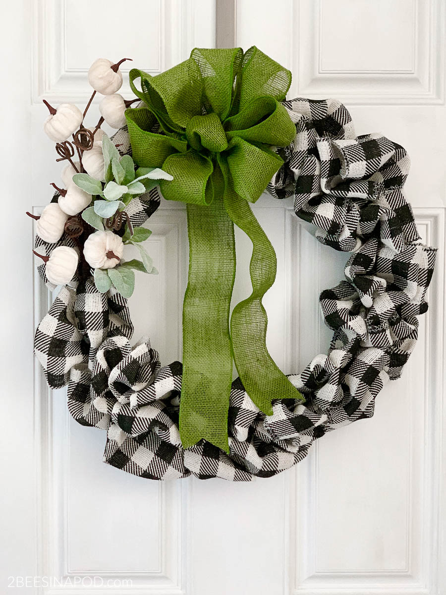 Buffalo check bubble wreath decorated with white pumpkins and a green bow