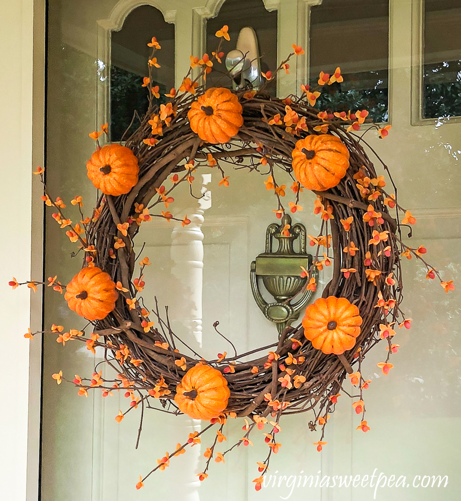 Fall grapevine wreath decorated with pumpkins and bittersweet