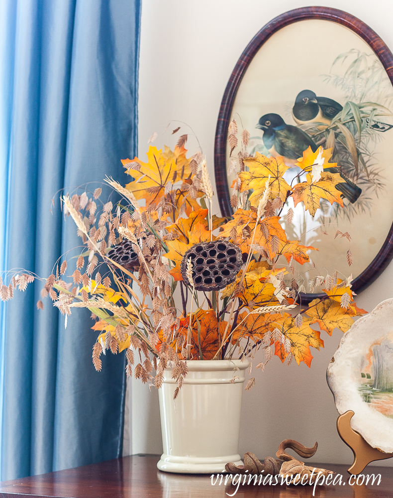 Fall arrangement with orange leaves, lotus pods, and wheat