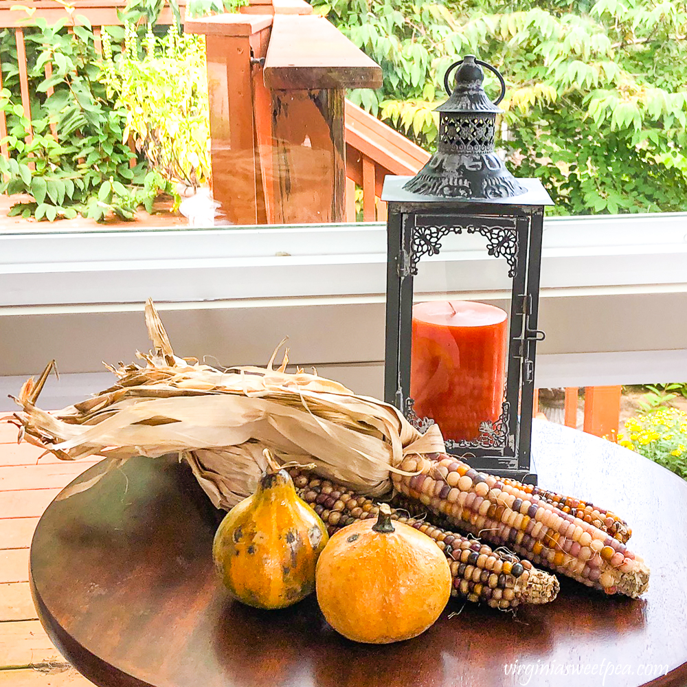 Indian corn, dried gourds, and a metal lantern holding an orange candle