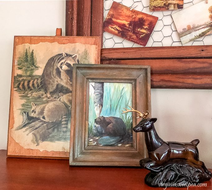 Vintage Avon stag cologne bottle with a beaver painting and a raccoon print decoupaged to a board.