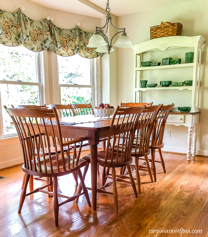 Breakfast room with a cherry table and chairs, white buffet with a collection of green pottery with a large picnic basket
