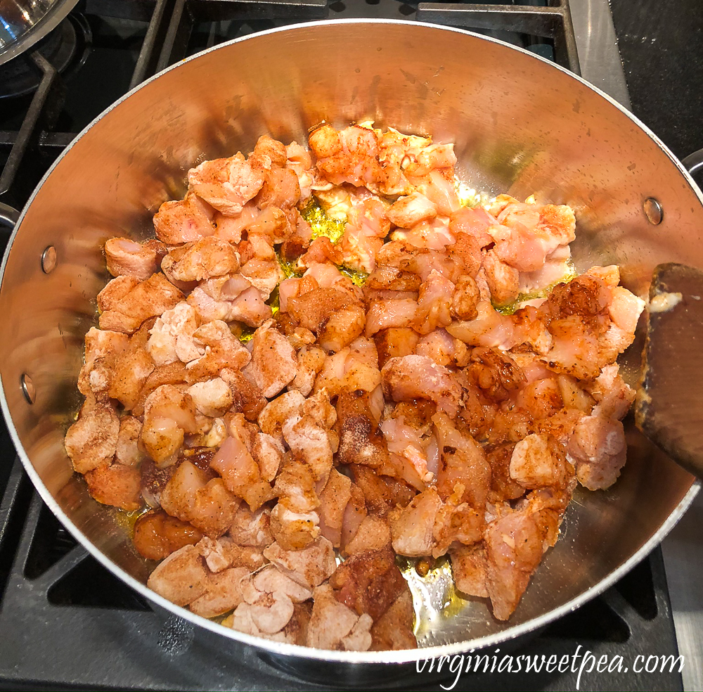 Chicken coated with flour and fajita seasoning in a pot to be browned