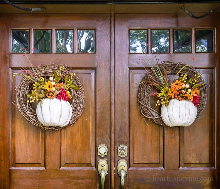 Two fall wreaths with pumpkins and fall florals on double doors.