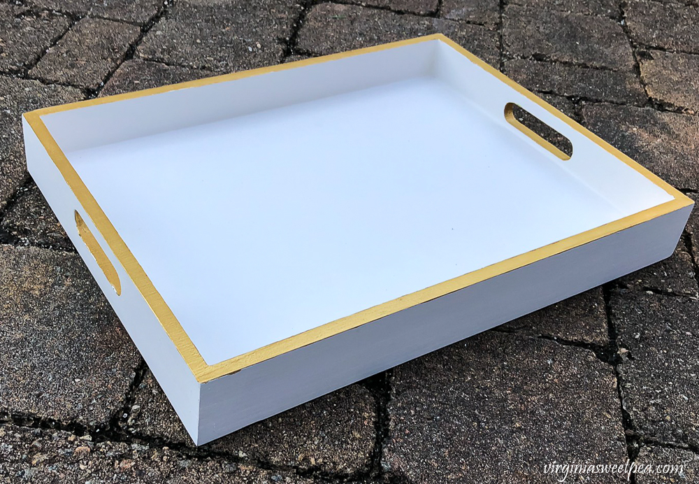 Wooden tray painted white with the edges and handles accented in metallic gold paint.