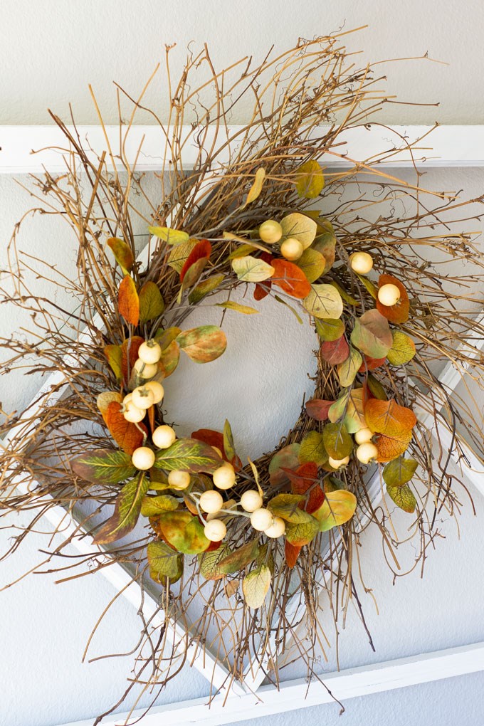 Twiggy fall wreath decorated with faux fall leaves and white berry picks