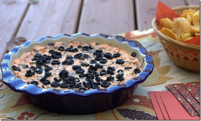 Dip made with spinach, salsa, cream cheese, Monterey Jack cheese, and sprinkled with olives.