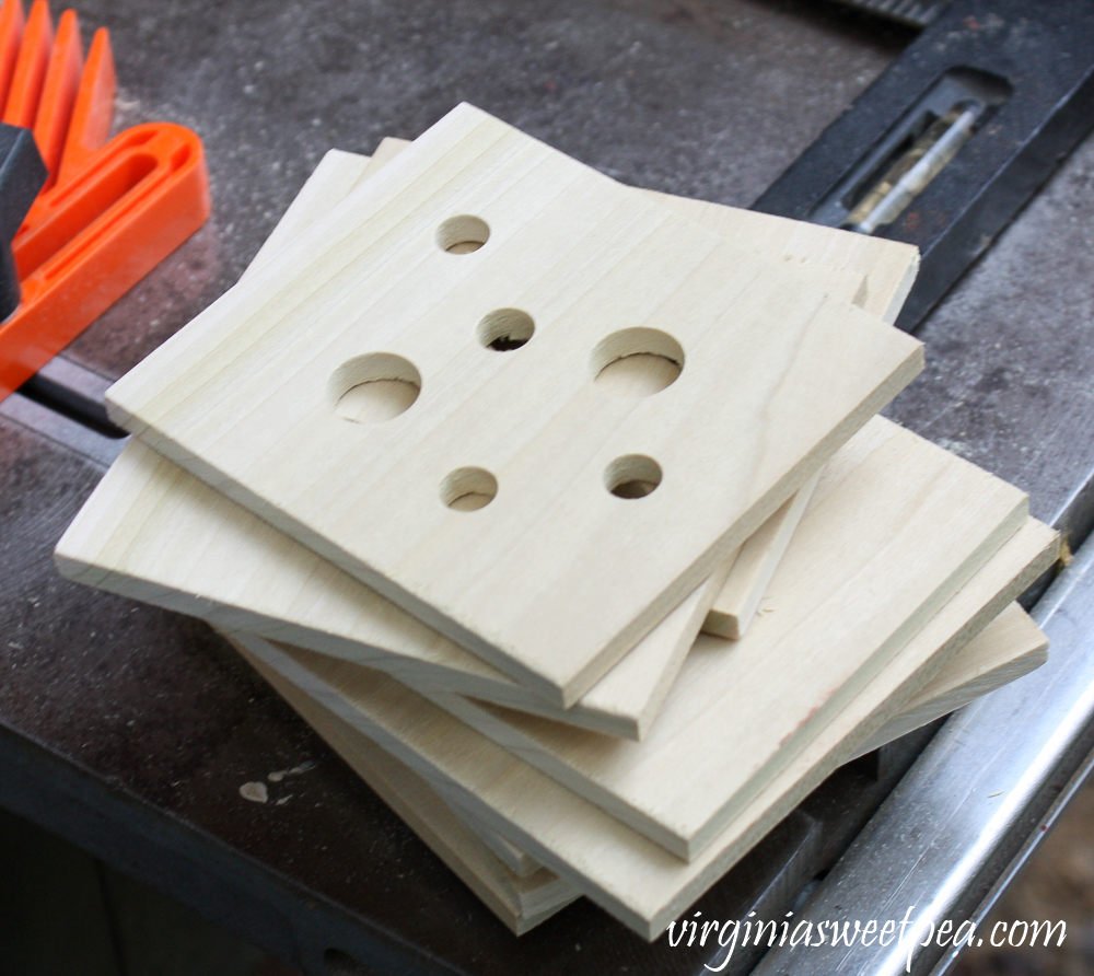 Stack of square wood pieces with holes cut in them of varying sizes