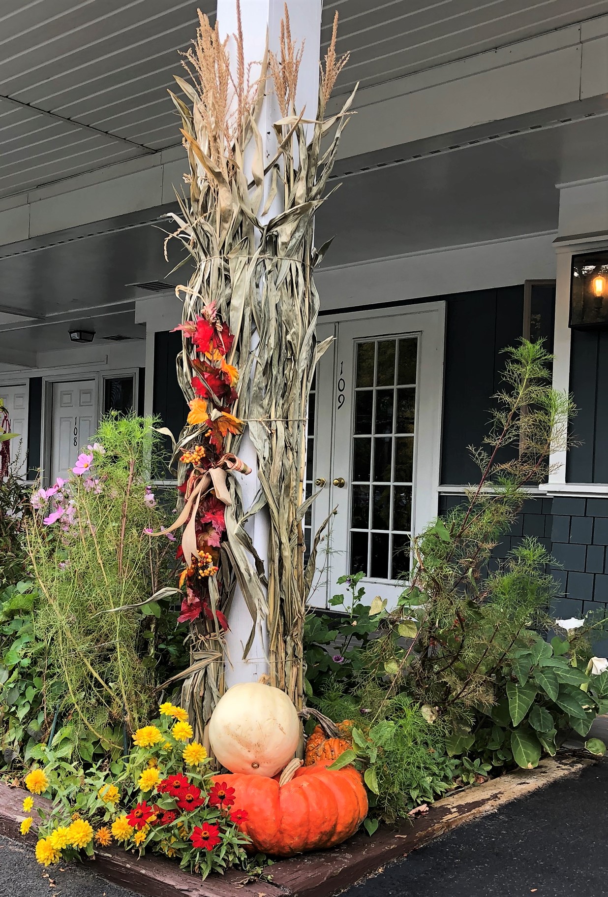 Cornstalks tied to a column with pumpkins and flowers