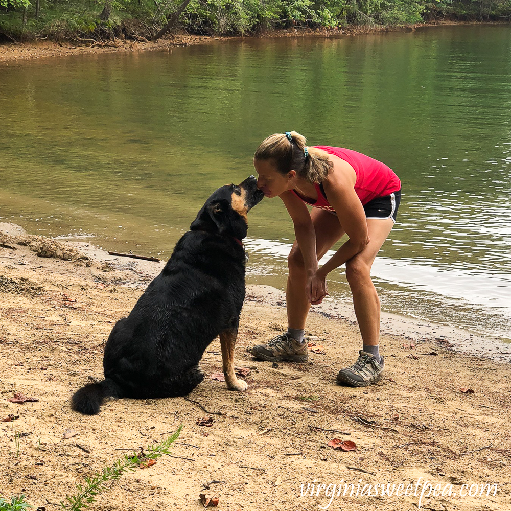 Woman kissing a dog beside a lake