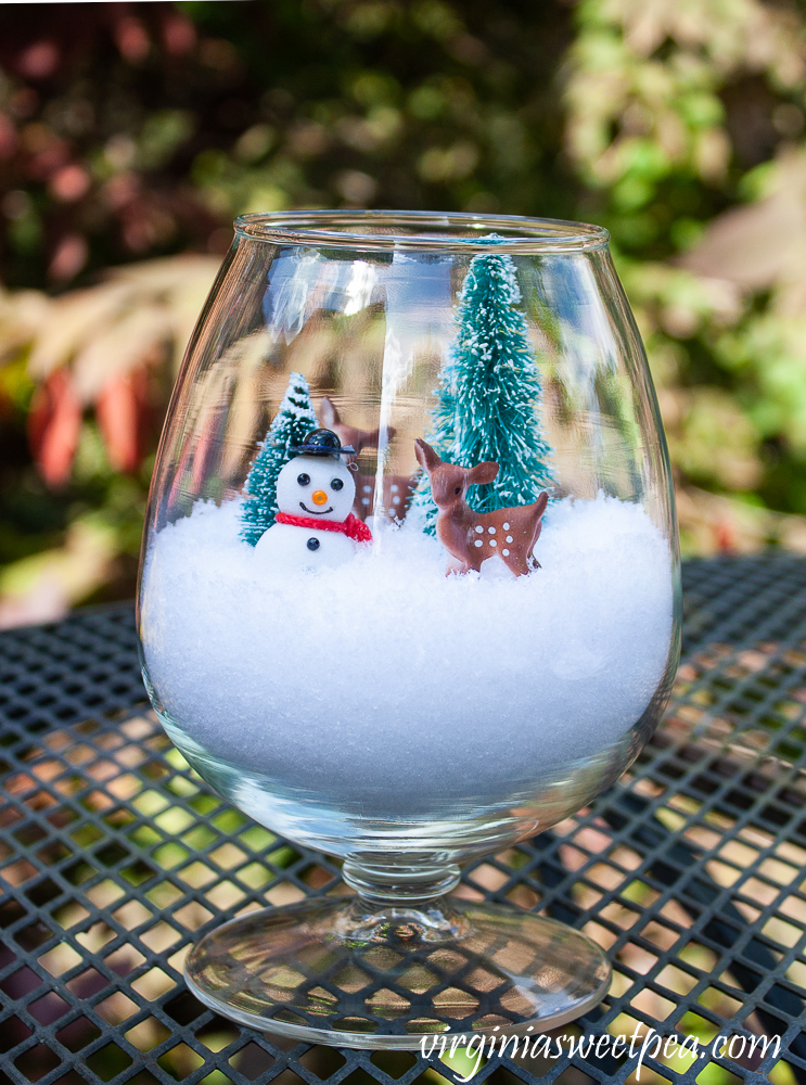 Brandy sniffer with snow, two miniature trees, deer, and a snowman