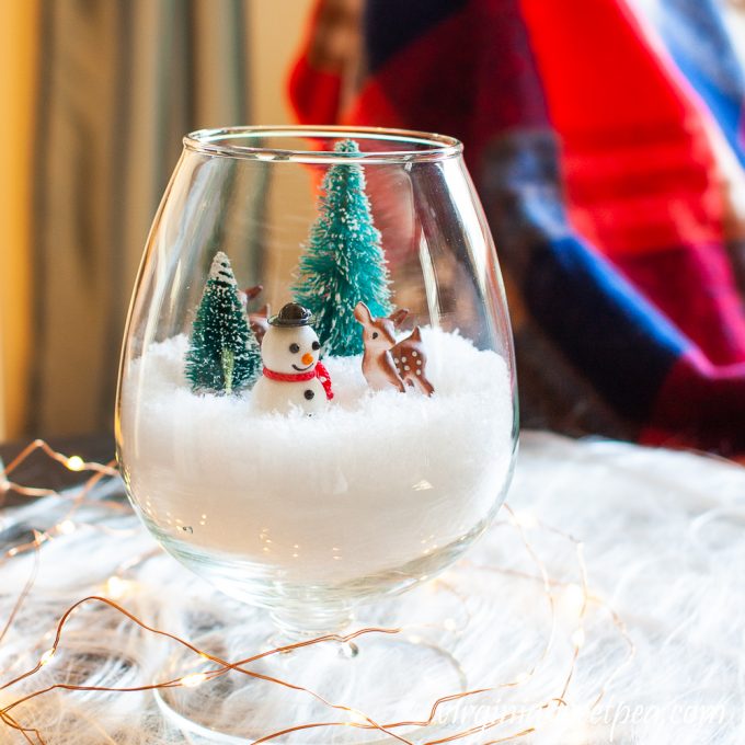 Winter scene in a brandy sniffer surrounded by twinkle lights.