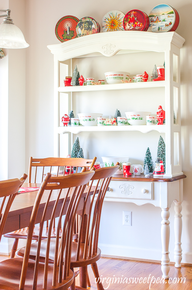 Hutch decorated for Christmas with vintage punch bowls, vintage Santas, bottlebrush trees, and vintage Christmas tins