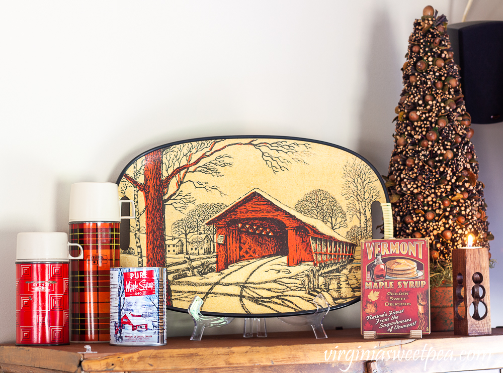 Red thermoses, covered bridge tray, tree decorated with acorns and twigs, handmade snowman candle holder, and Vermont maple syrup postcard.