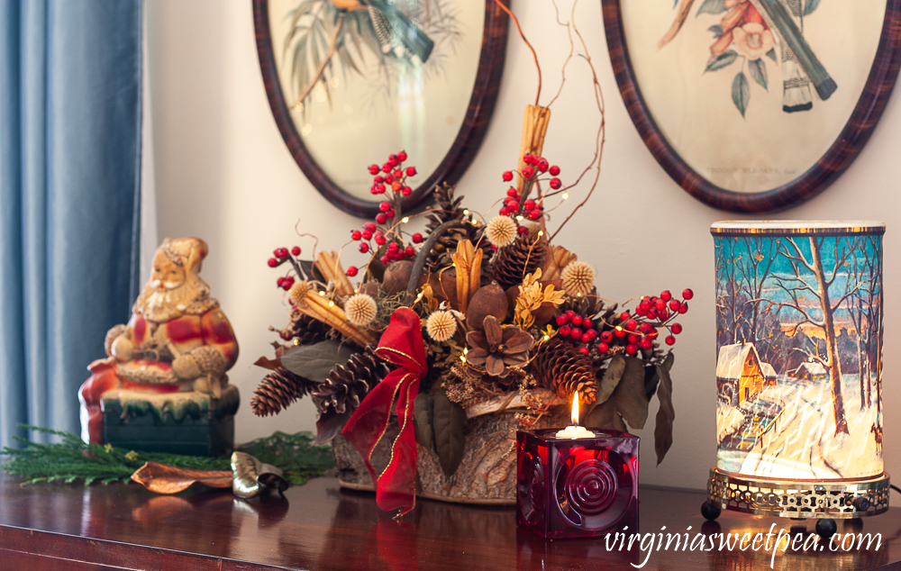 Vintage Econolite motion lamp, red Blenko glass candle holder, and birch bark basket with dried natural elements and Santa bank