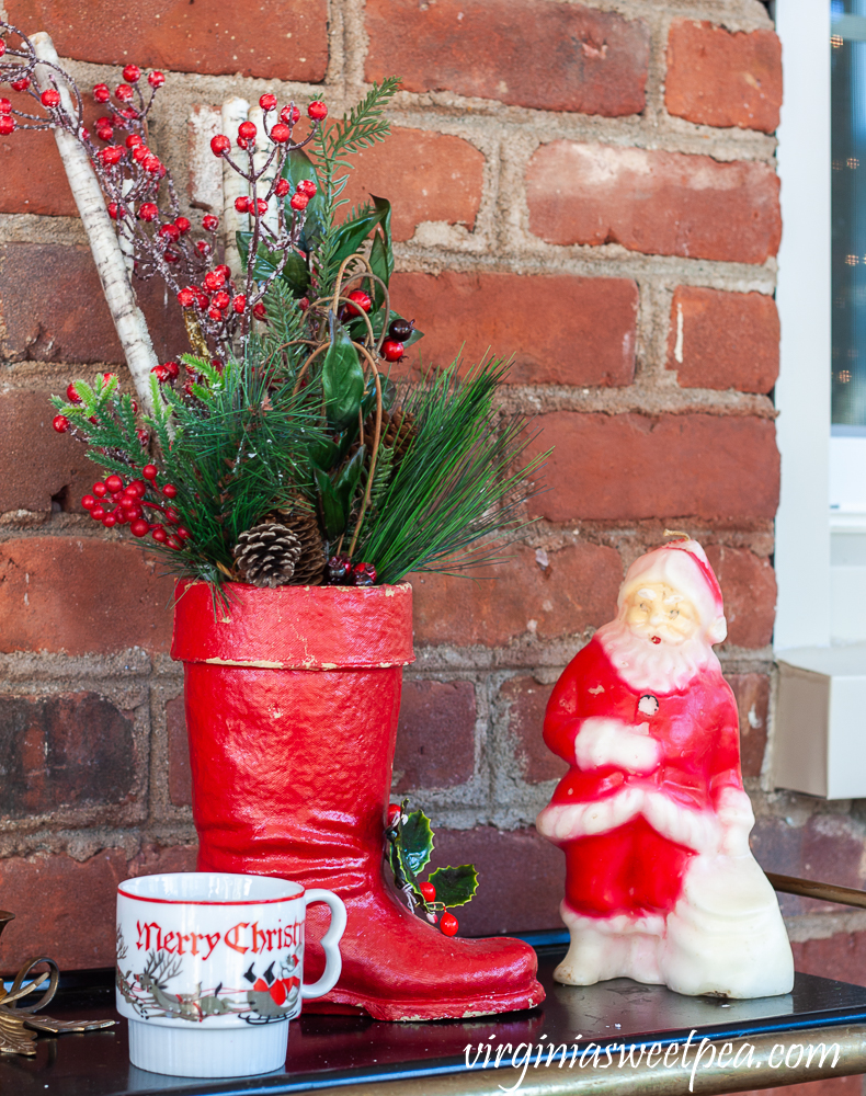 Large vintage Santa boot with greenery, vintage Christmas mug, and vintage Santa candle