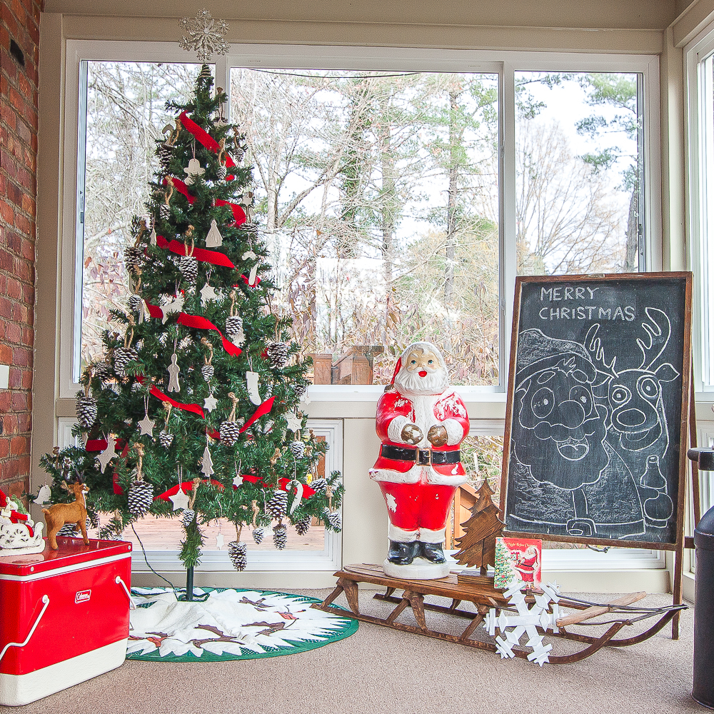 A porch decorated for Christmas with a tree with handmade ornaments, handmade tree skirt, blowmold Santa, and more vintage Christmas decor