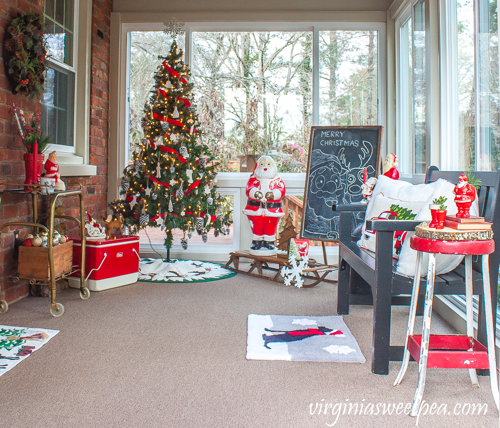 Porch decorated for Christmas with a tree and a Santa theme