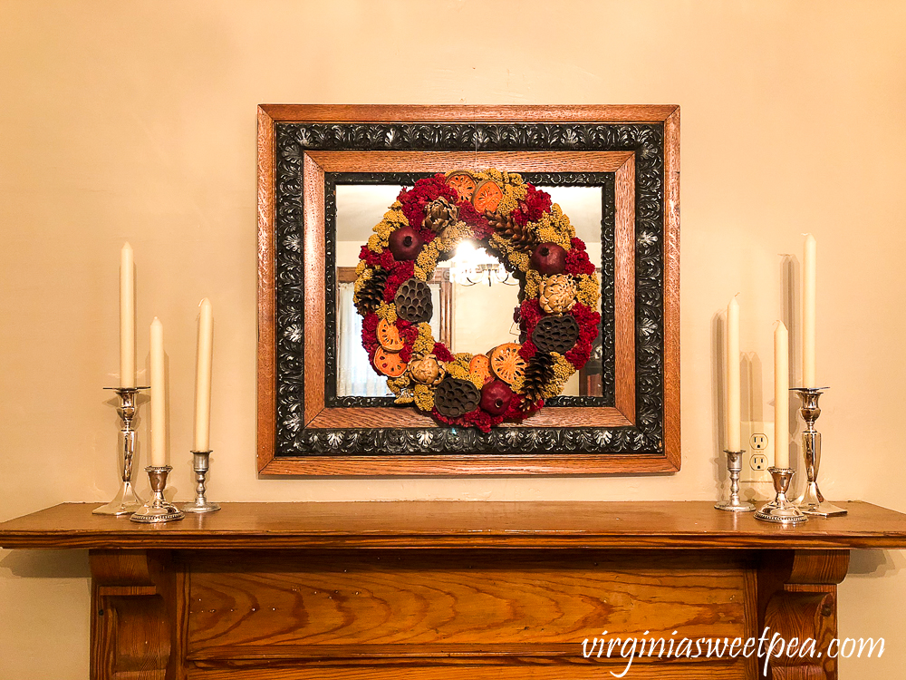 Mantel Decor in a 1912 House with dried floral wreath on an antique mirror with silver candlestick holders and white candles