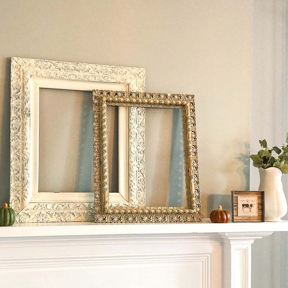 Two antique frames, one white, one gold, with a pumpkin, cow picture, and white pitcher filled with Eucalyptus
