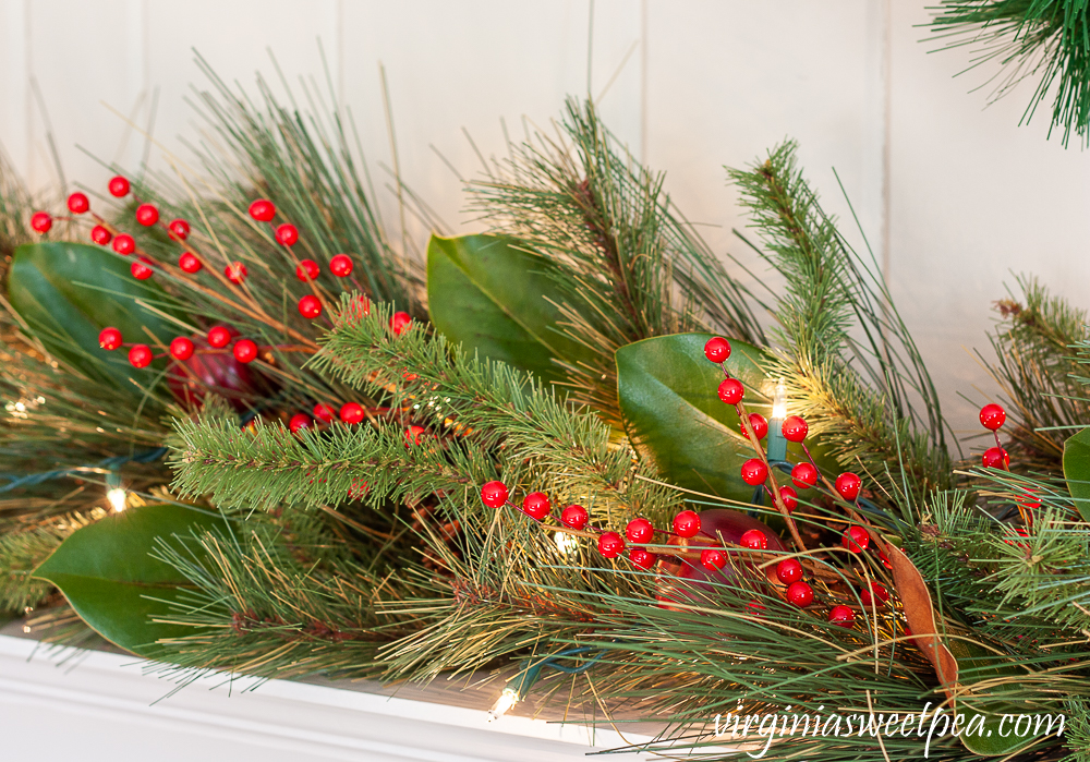 Realistic faux evergreen garland embellished with faux berries, apples, and Magnolia leaves.