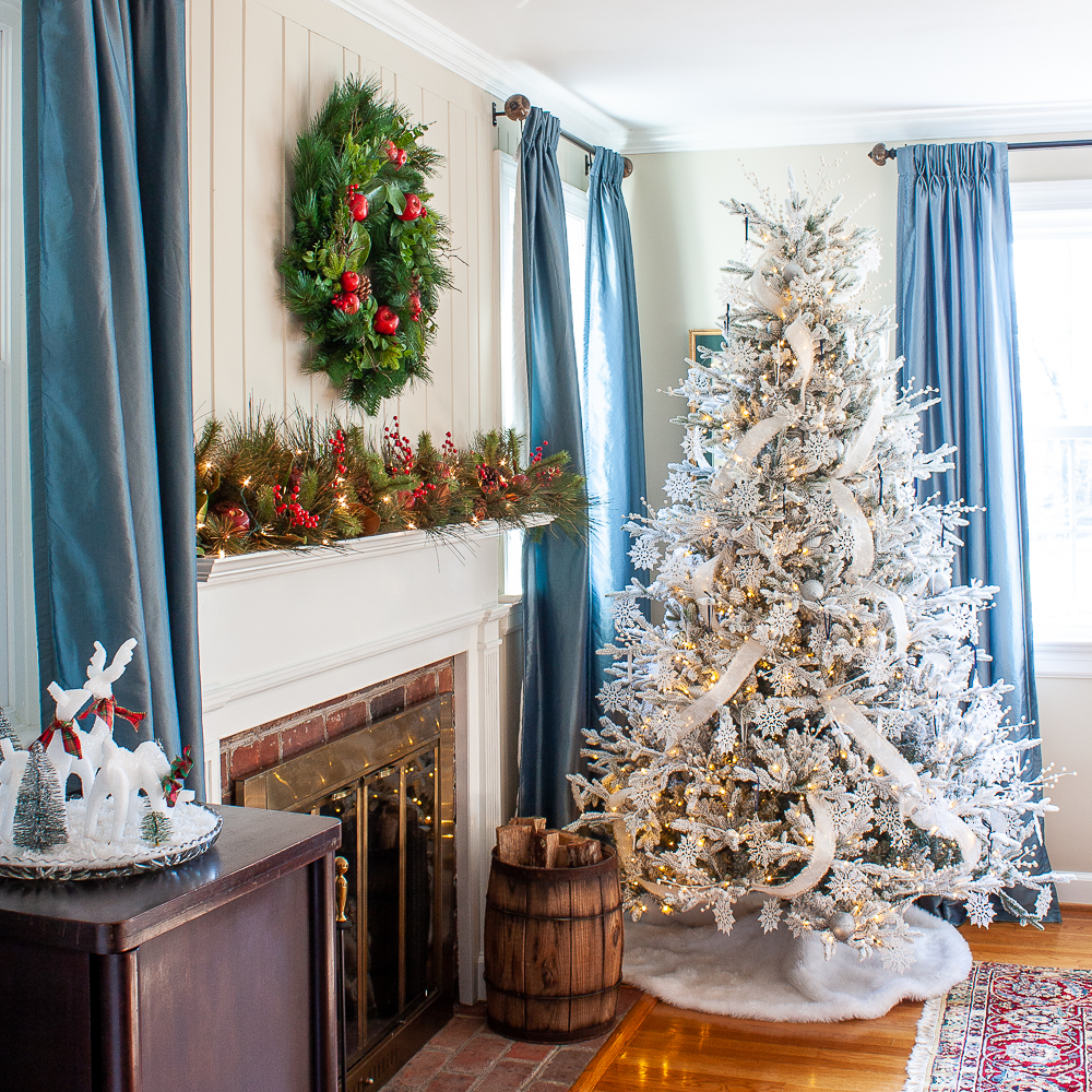 Flocked Christmas tree beside a mantel decorated for Christma