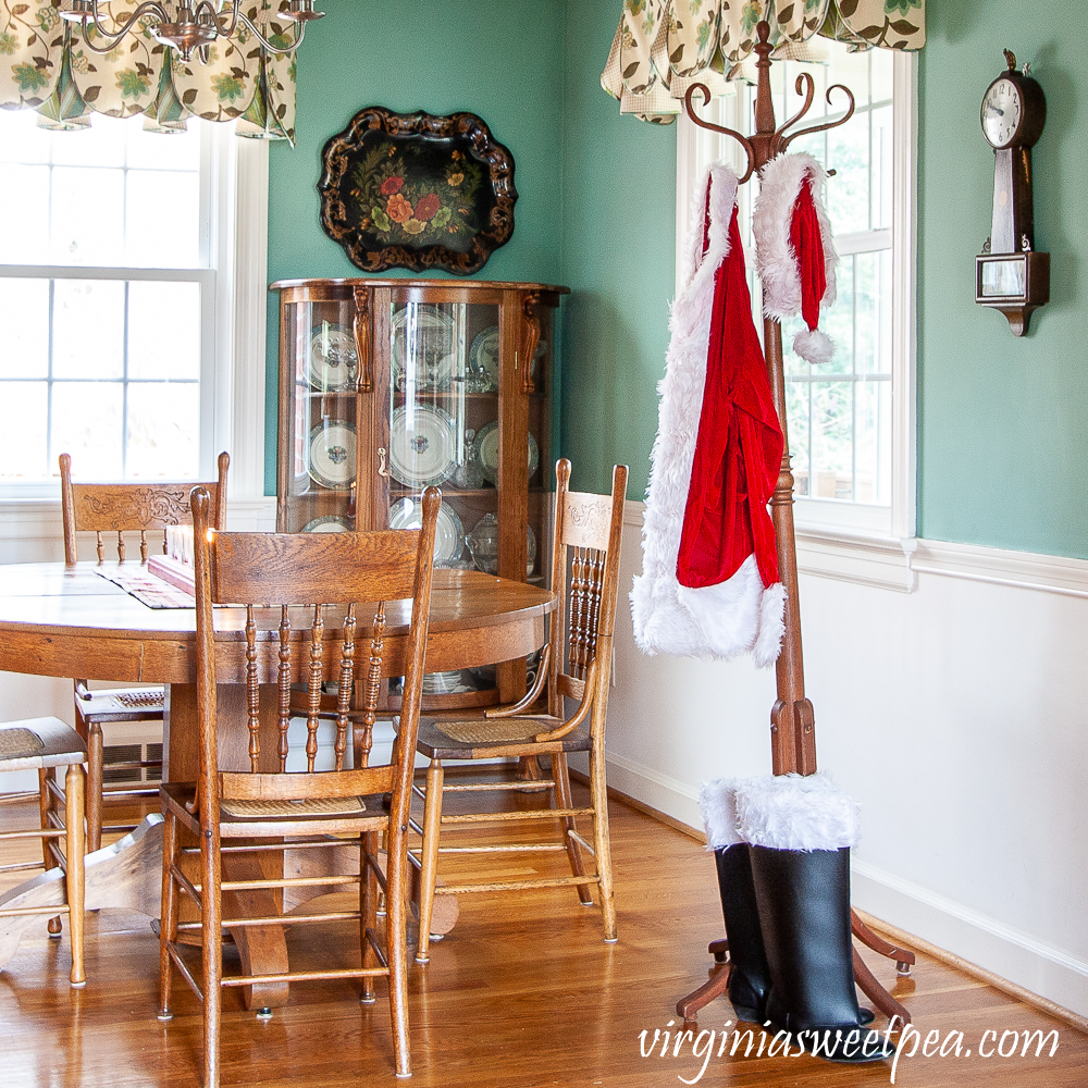 A Santa suit hanging on a coat rack along with Santa's boots