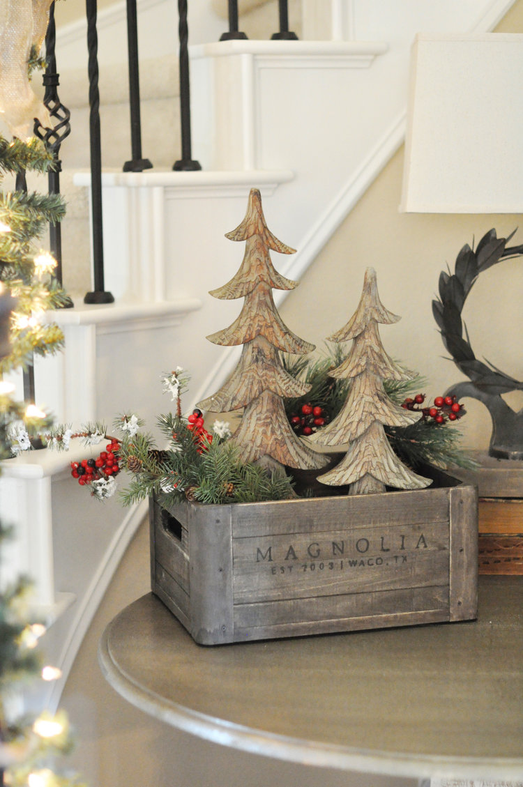 Crate decorated for Christmas with two wooden trees and greenery.