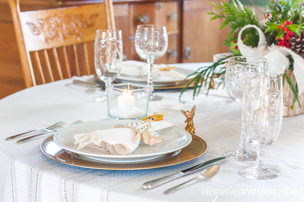 Christmas table set with vintage silver, vintage 1970s angels, vintage Rocksharp Villars crystal, lighted candles, and a Christmas centerpiece