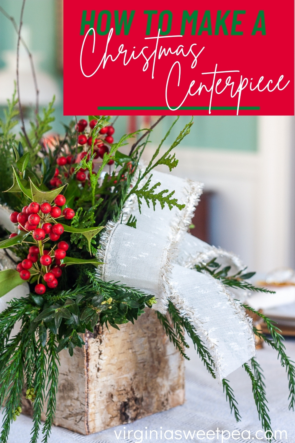 Christmas table centerpiece in a birch box with greenery, white bows, holly, pinecones, and twigs.