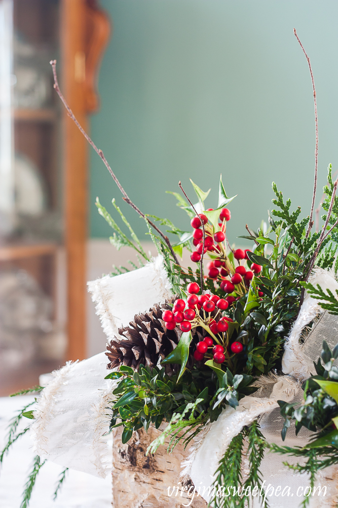 Side view of a Christmas centerpiece in a Birch bark box with greenery, Holly, twigs, and white bows