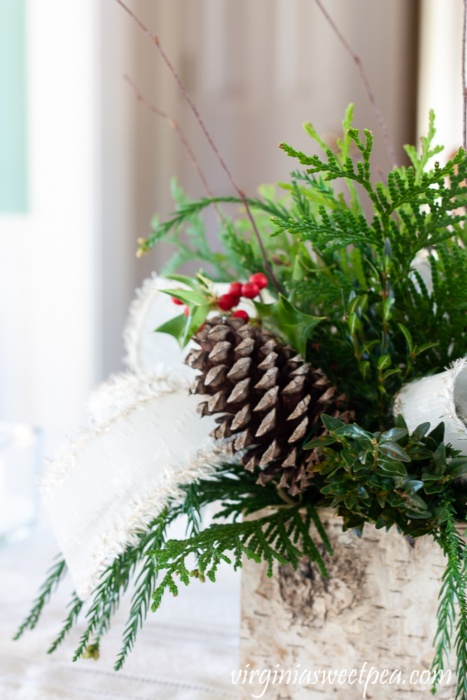 Side view of a Christmas centerpiece in a Birch bark box with greenery, Holly, twigs, and white bows