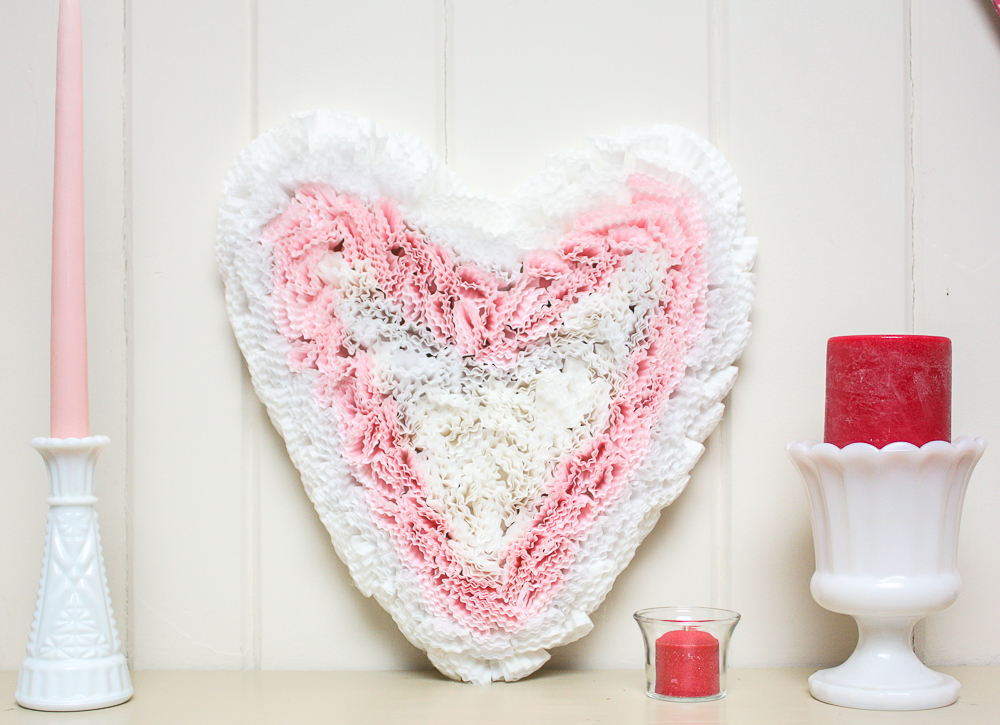 Valentine's Day cupcake liner heart on a mantel with milk glass vases and candles