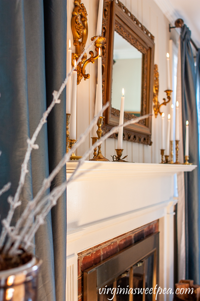 Mantel Decorated for winter with gold, brass, and white candles.