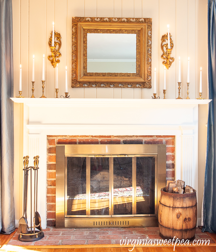 Mantel Decorated for winter with gold, brass, and white candles.