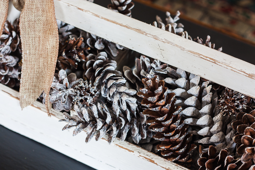 Vintage toolbox decorated for winter with glittered and snow-kissed pinecones.