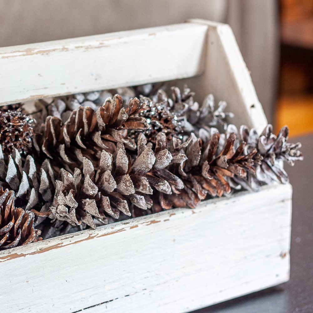 Vintage toolbox decorated for winter with glittered and snow-kissed pinecones.