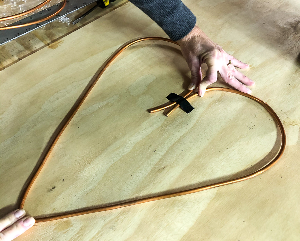 Heart formed from copper wire taped to a piece of plyboard with electrical tape