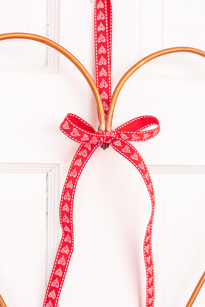 Valentine's Day red and white heart ribbon decorating a copper pipe heart wreath